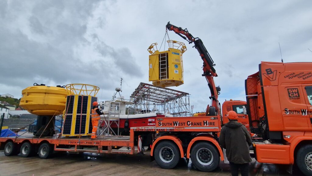 Yellow data buoy piece being lifted by crane on to truck