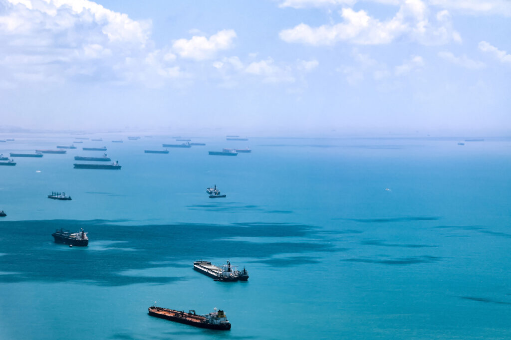 Container ships in a bay surrounded by light blue ocean